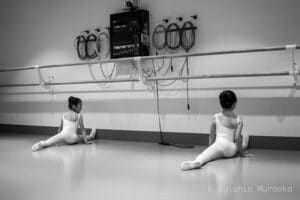 Two girls stectching in ballet class
